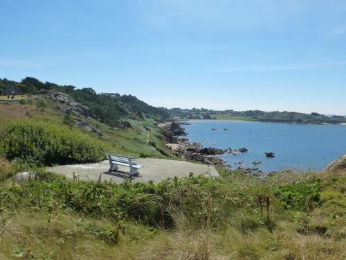 a bench sitting on a hill next to a body of water at House in Plougasnou near Stunning Beaches in Plougasnou