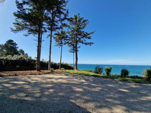a road with trees and the ocean in the background at House in Plougasnou near Stunning Beaches in Plougasnou