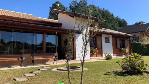 ein Haus mit einem Baum im Vorgarten in der Unterkunft Aconchegante casa em Monte Verde in Monte Verde