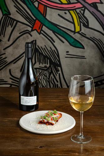 a bottle of wine and a plate of pizza and a glass at Estancias Sierravita in Valle de Guadalupe