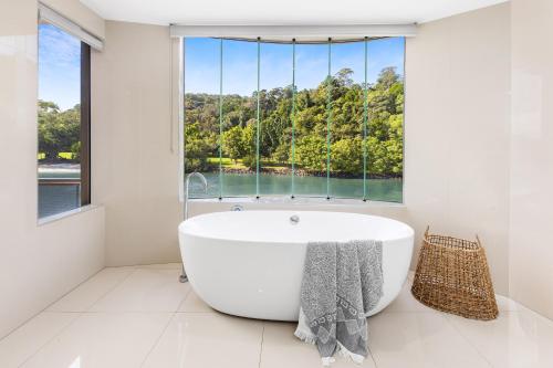 ein weißes Badezimmer mit einem großen Fenster und einer Badewanne in der Unterkunft 31 Witta Circle, Noosa Heads in Noosa Heads