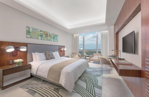 イロイロにあるリッチモンド ホテル イロイロのベッドルーム(大型ベッド1台付)、リビングルームが備わります。