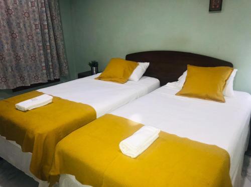 two beds in a room with yellow sheets and pillows at Hotel Casa Blanca in León