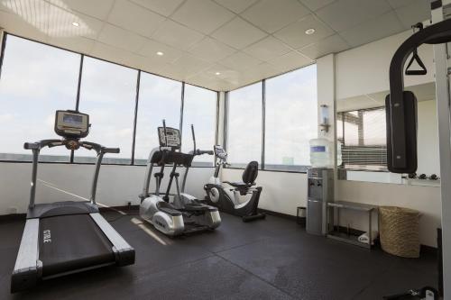 a gym with treadmills and ellipticals in a room with windows at Best Western Elyon Colombo in Colombo