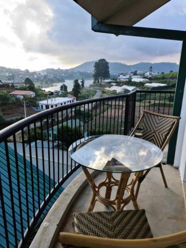 a table and chairs on a balcony with a view at Lake Infinity Luxury Condos in Nuwara Eliya