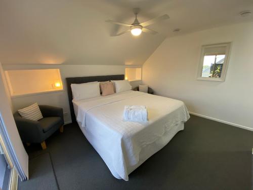sypialnia z dużym białym łóżkiem i krzesłem w obiekcie Rainbow Beach Dream Studio Motel Style Apartment w mieście Rainbow Beach