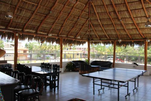 a restaurant with tables and chairs and a large roof at Hotel & Suites VAYOR in San Patricio Melaque