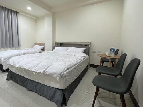 a bedroom with two beds and a table and chairs at 金門民宿 x 花藝雅築 The Flower Hut in Jinhu