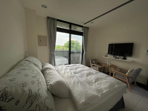 a bedroom with a bed and a tv and a window at 金門民宿 x 花藝雅築 The Flower Hut in Jinhu
