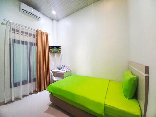 a bedroom with a green bed and a sink at Hometown Residence in Bandar Lampung