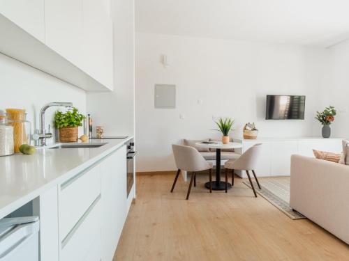 a kitchen and dining room with white cabinets and a table at Armonta Residences by BeCyprus in Limassol