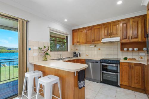 a kitchen with wooden cabinets and a view of the water at Punt House - riverfront home with ramp access in Dunbogan