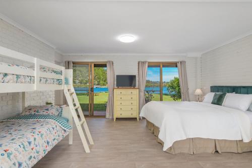 a bedroom with a bed and a bunk bed at Punt House - riverfront home with ramp access in Dunbogan