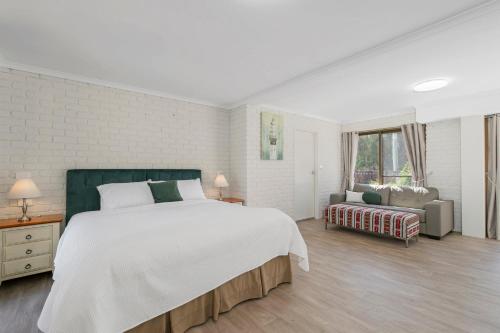 a white bedroom with a large bed and a couch at Punt House - riverfront home with ramp access in Dunbogan