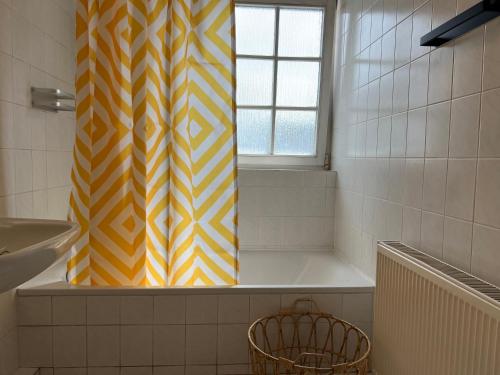 a bathroom with a yellow and white shower curtain at Cozy-Livings viel Platz, großer Balkon, STELLPLATZ, Küche in Bad Homburg vor der Höhe