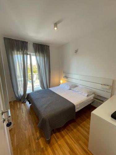 sypialnia z łóżkiem i dużym oknem w obiekcie Apartments Mali Ivo w Nin