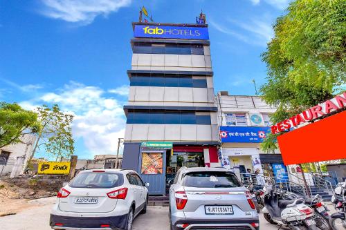 two cars parked in front of a tall building at FabExpress Dosa Plaza in Udaipur