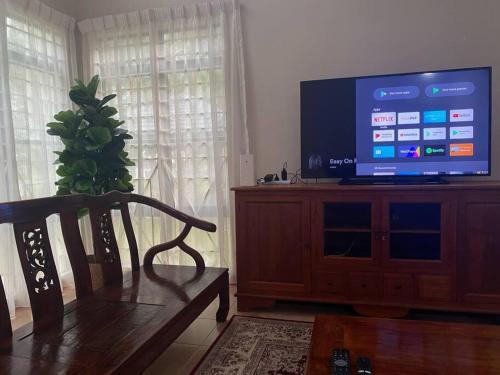 a living room with a television on a wooden entertainment center at Villa Teratai 878 @ A'Famosa Resort in Kampong Alor Gajah