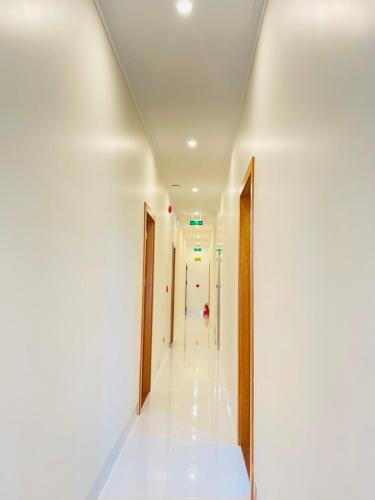 a hallway in a building with white walls and wooden doors at Khách sạn Sớm Phú Quý 2 - Phan Rang in Phan Rang