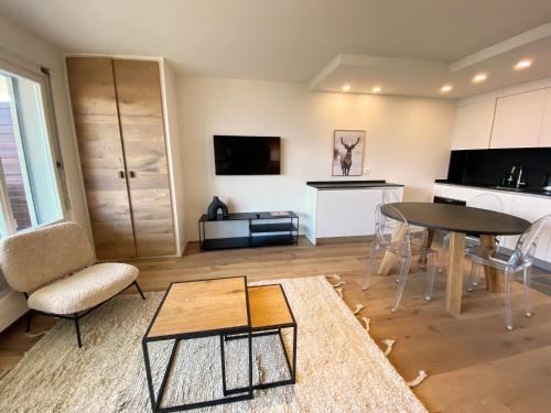 ein Wohnzimmer mit einem Tisch und einer Küche in der Unterkunft Apartment Del Sol Elysée 4 Crans Montana Switzerland in Crans-Montana