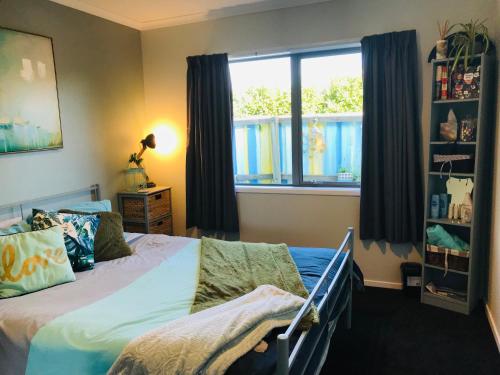 een slaapkamer met een bed en een raam bij A Little Bit Beachy Modern Guest Room and Private Toilet in Christchurch