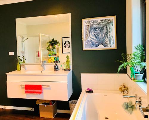 a bathroom with a sink and a tub and a mirror at A Little Bit Beachy Modern Guest Room and Private Toilet in Christchurch