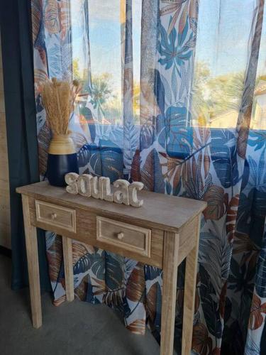 une table en bois avec un vase au-dessus dans l'établissement Chalet Cosy à 10min des plages- Soulac-sur-Mer, à Soulac-sur-Mer