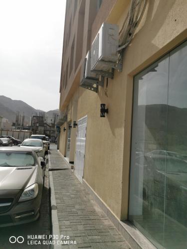 a building with cars parked on the side of it at Amazing 2BR pent house flat with mountain view in Muscat