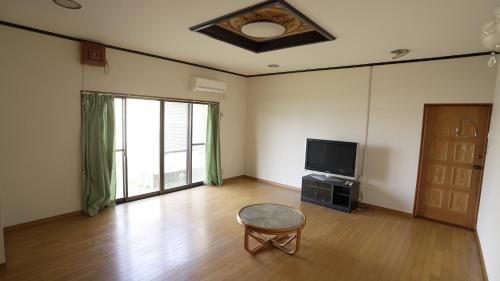 a living room with a chair and a television at 楠のおうち in Yokkaichi