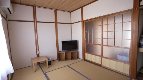 an empty room with a tv and a table and a window at 楠のおうち in Yokkaichi