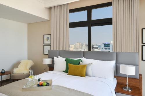 a bedroom with a white bed with a large window at Le Mirage Downtown in Doha