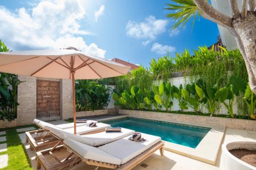 a pool with a chair and an umbrella next to a swimming pool at Puspa Ayu Villas & Apartments in Kuta