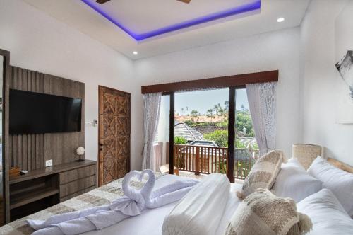 a living room with a white bed and a tv at Puspa Ayu Villas & Apartments in Kuta