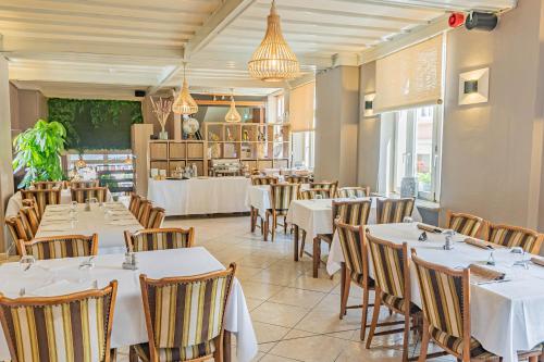 a dining room with white tables and chairs at H&ocirc;tel Le Petit Po&egrave;te in Echternach