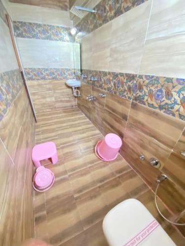 a bathroom with a toilet and pink stools at Hotel Gomti Dwarka in Dwarka