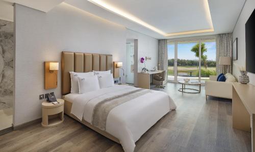 a bedroom with a large white bed and a living room at Zoya Health & Wellbeing Resort in Ajman 