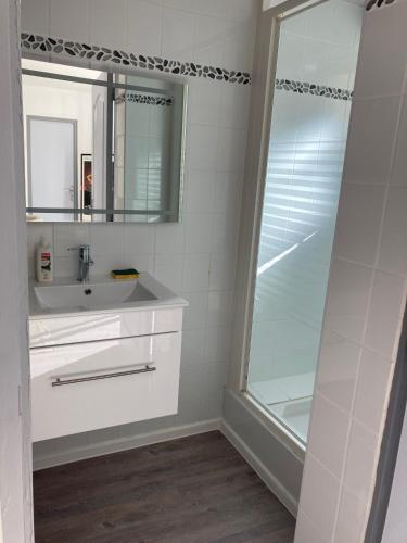 une salle de bain blanche avec un lavabo et une douche dans l'établissement Trés belle suite prés mer et golf avec piscine, à Saint-Côme