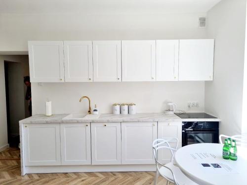 a white kitchen with white cabinets and a table at Sun and holidays apartament Abrahama in Gdynia