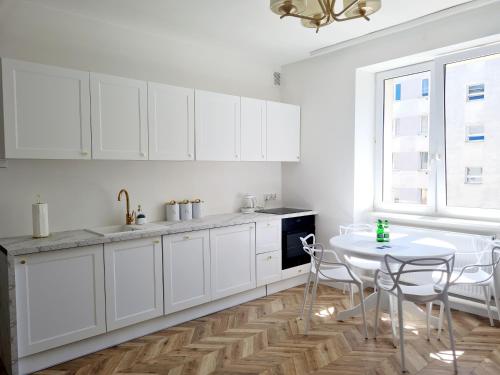 cocina con armarios blancos, mesa y ventana en Sun and holidays apartament Abrahama, en Gdynia