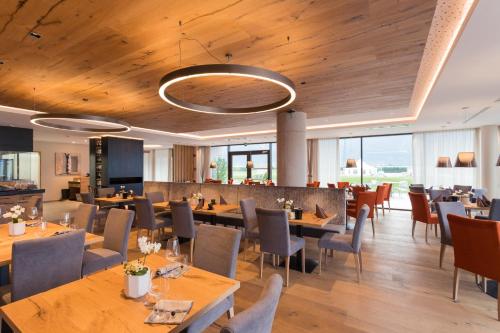 een restaurant met houten plafonds en tafels en stoelen bij The Lodge Sporthotel - Golfclub Eppan in Appiano sulla Strada del Vino