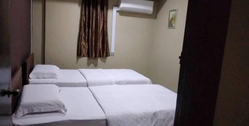 two beds in a hotel room with white sheets at Tabin Lodge in Lahad Datu