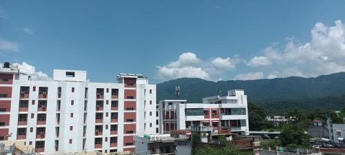 a group of buildings with mountains in the background at Krishnabalram wellness & Ayurveda centre in Rishīkesh