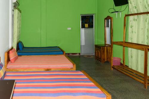 a bedroom with two beds and a green wall at Gnanam Holiday Inn in Pasikuda
