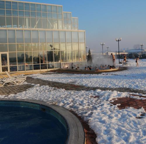a building with a snow covered fountain in front of a building at Hotel Alinalex - Paradisul Acvatic in Braşov