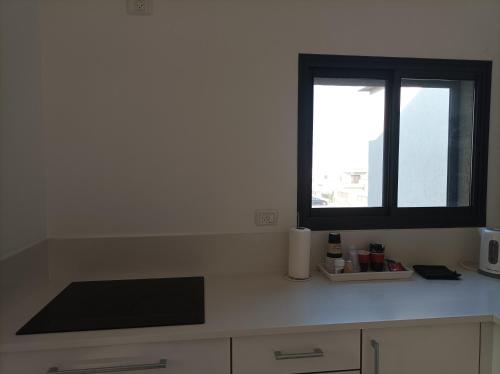 uma cozinha com uma janela e um balcão branco em נוגה בגולן em Katzrin