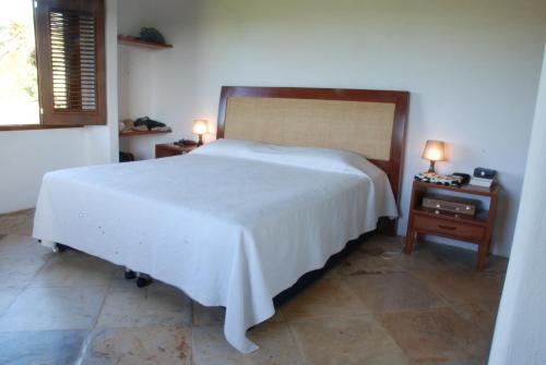 1 dormitorio con 1 cama blanca grande y mesita de noche en Vila Kitepirinha, en Flecheiras
