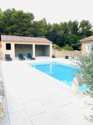 une piscine avec deux chaises et une maison dans l'établissement Jolie maison de 110 m 2, pour 6 personnes, au calme, avec piscine, à Les Cordiers