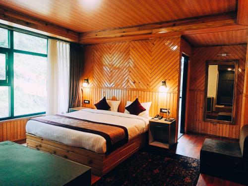 um quarto com uma cama num quarto com paredes de madeira em Rufina Lachung Kunga em Lachung