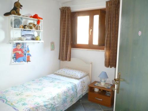 ein kleines Schlafzimmer mit einem Bett und einem Fenster in der Unterkunft Attico Bellavista in Santa Maria Navarrese