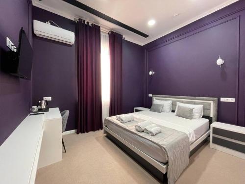 a bedroom with purple walls and a bed and a desk at Emin hotel in Fergana